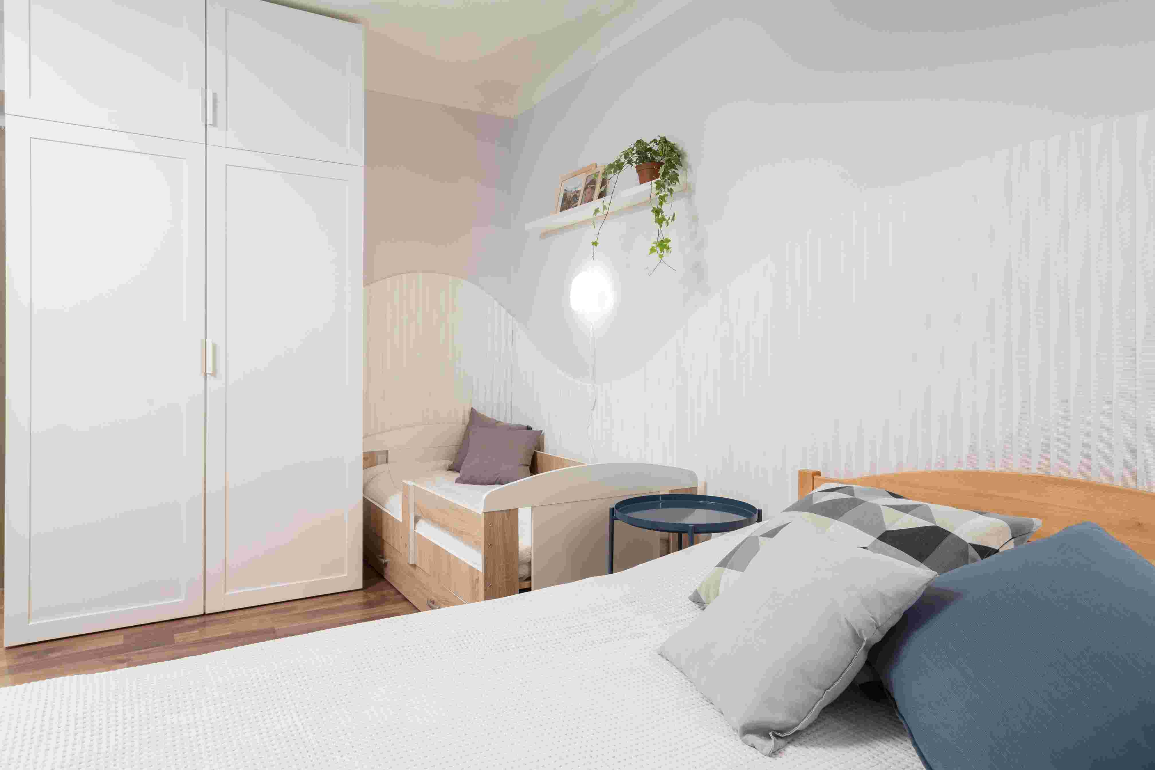 Dětský pokoj s dřevěnými postelemi, bílou šatní skříní a světlým moderním interiérem.